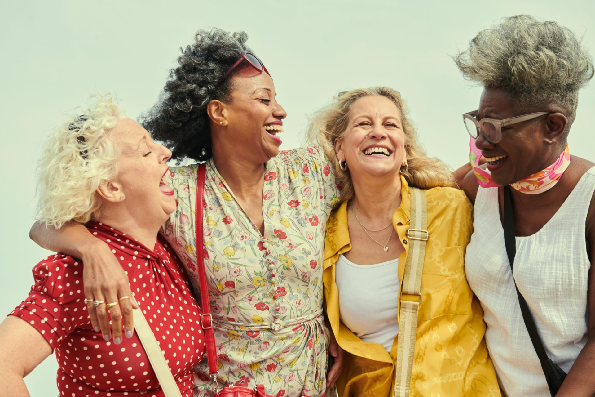 Four women in the second half of life laughing together, arms around one another